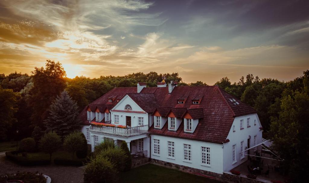 une grande maison blanche avec un toit rouge dans l'établissement Dwór w Bychowie, à Bychowo