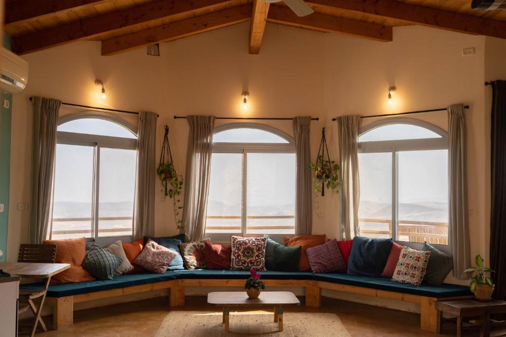 a living room with a blue couch in front of windows at Tambourine Guest house טמבורין גסט האוס in Tekoa