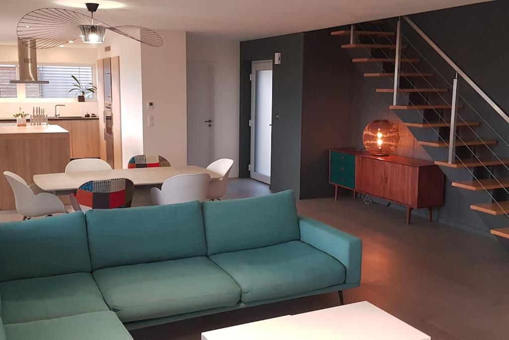 a living room with a blue couch and a staircase at Maison Passive avec piscine proche Colmar in Logelheim