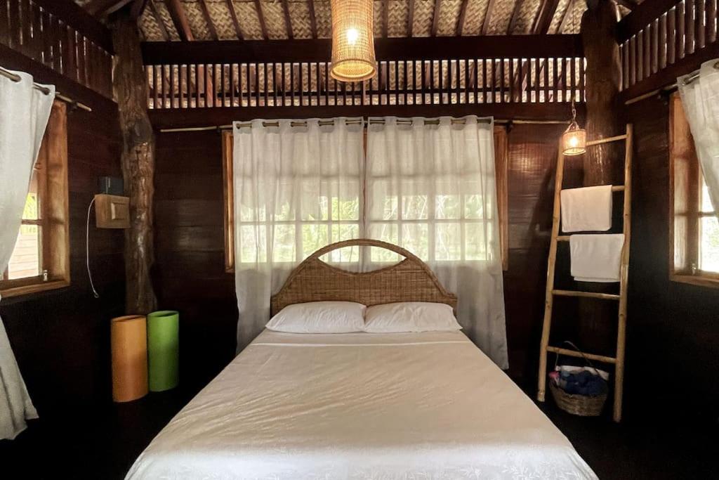 a bedroom with a bed in a room with a window at Marahuyo - Off-grid, beachfront, private cabin in Taytay