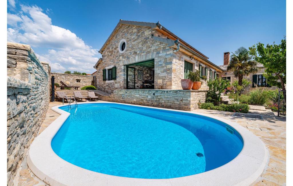 a swimming pool in front of a stone house at Stunning Home In Lisicic With 3 Bedrooms, Wifi And Outdoor Swimming Pool in Lisičići