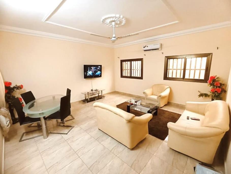 ein großes Wohnzimmer mit einem Tisch und Stühlen in der Unterkunft Résidence aux deux cocos in Lomé