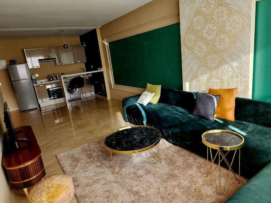 a living room with a green couch and two tables at Studio lumineux avec piscine/Gare casa oasis in Casablanca