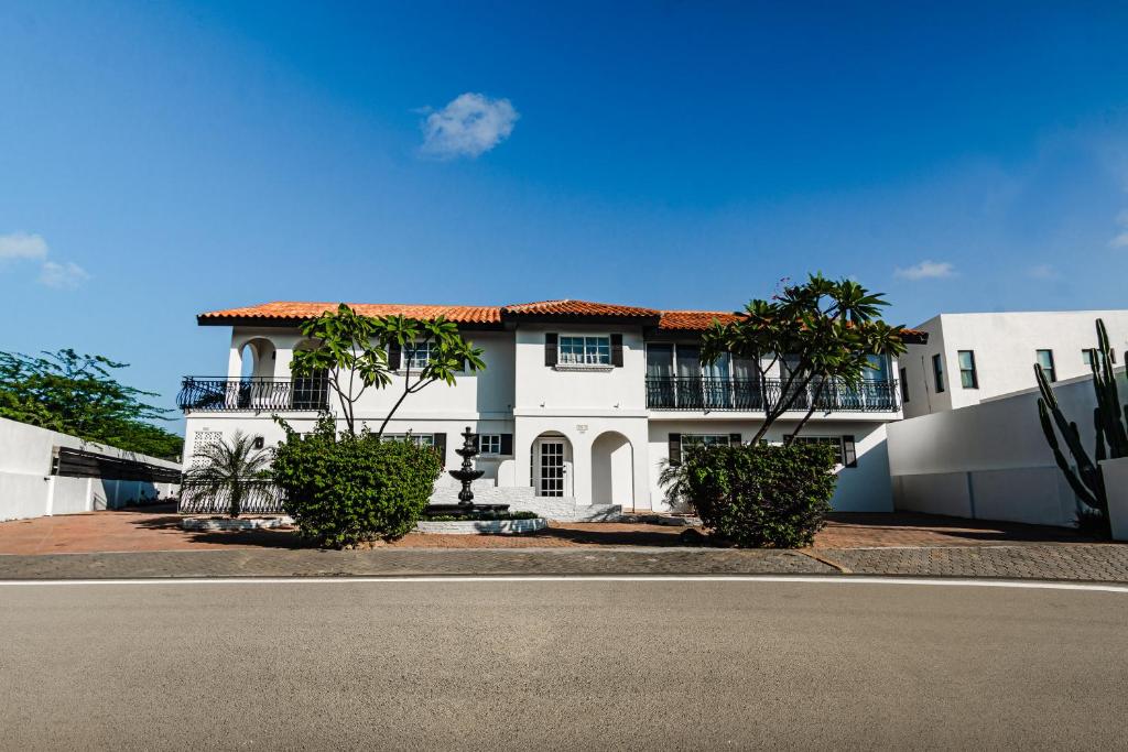 una casa blanca con árboles frente a una calle en Villa Fontana 1 & 2 en Palm-Eagle Beach