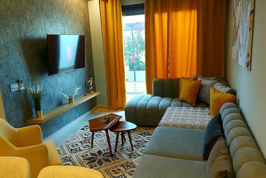 een woonkamer met een bank en een tv bij Appartement avec piscine et jacuzzi privé in Casablanca