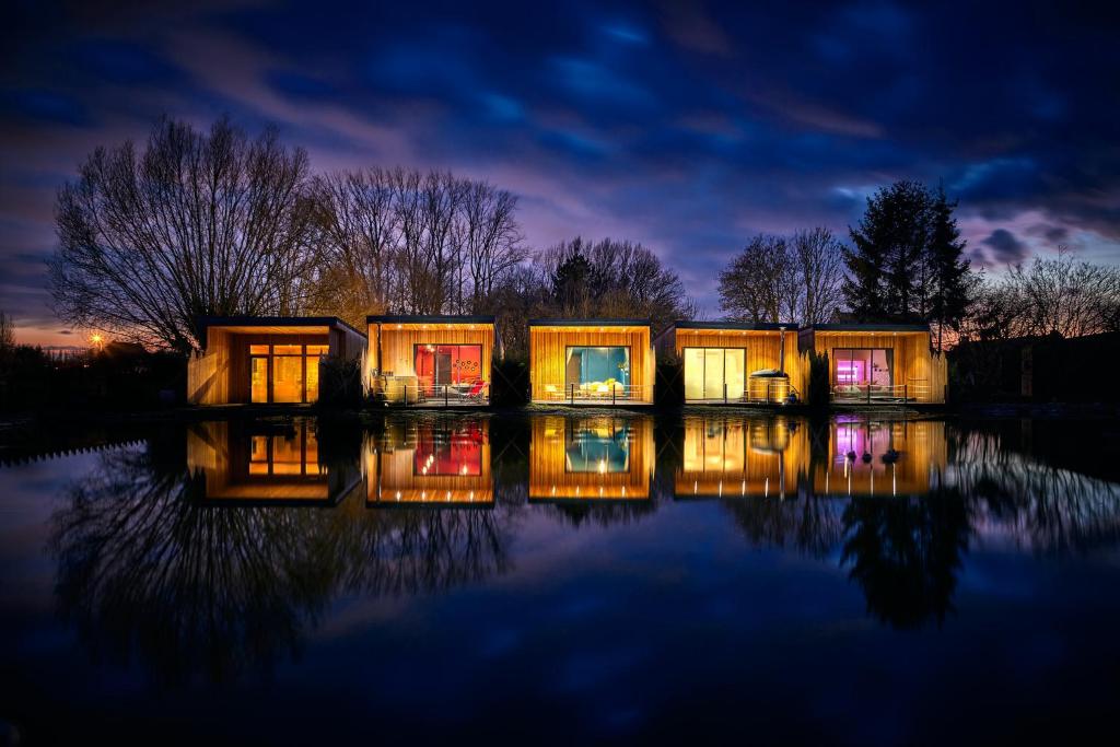 a group of tiny houses on the water at night at LE REFUGE - Le Domaine Wambrechies in Wambrechies