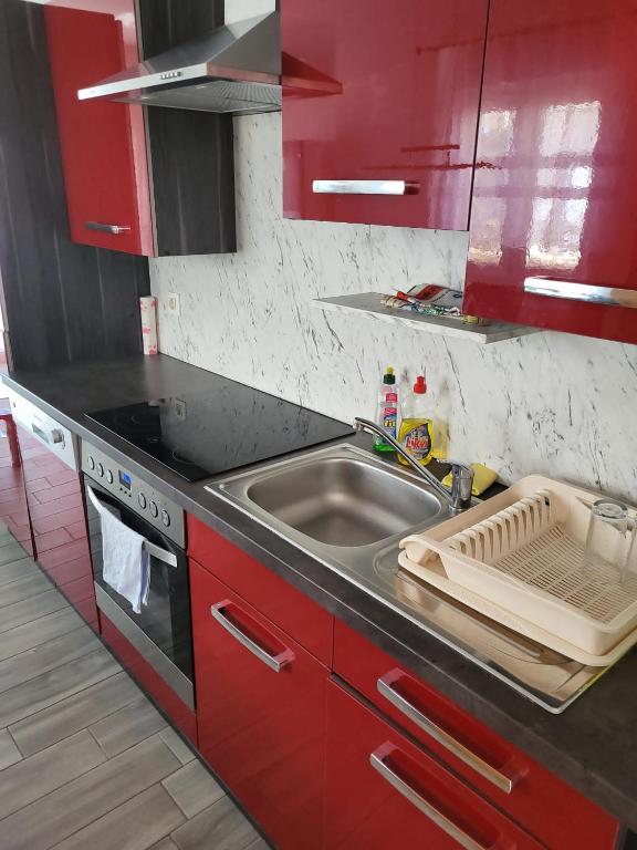 czerwona kuchnia ze zlewem i kuchenką w obiekcie Ferienappartment Mary w mieście Skunca