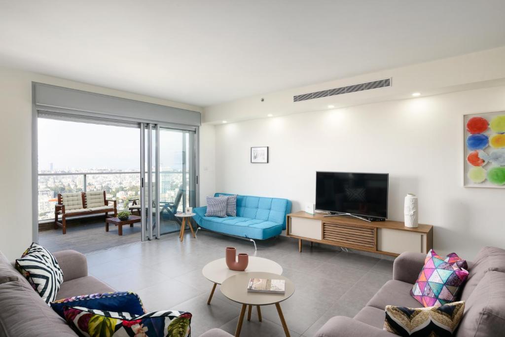 uma sala de estar com um sofá e uma televisão em Deluxe & Terrace with City Overview by FeelHome em Holon