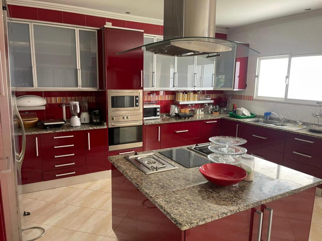 a kitchen with red cabinets and a granite counter top at Casa Luxuosa na Ilha do Mussulo in Belas