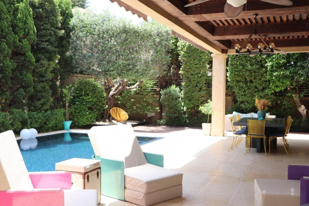 un patio con sillas y una piscina con pérgola. en The Peaceful Villa en Herzelia 