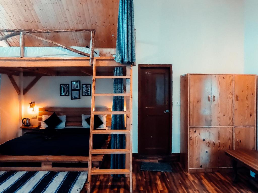 a bedroom with two bunk beds and a ladder at Roamate Hostel, Old Manali in Manāli