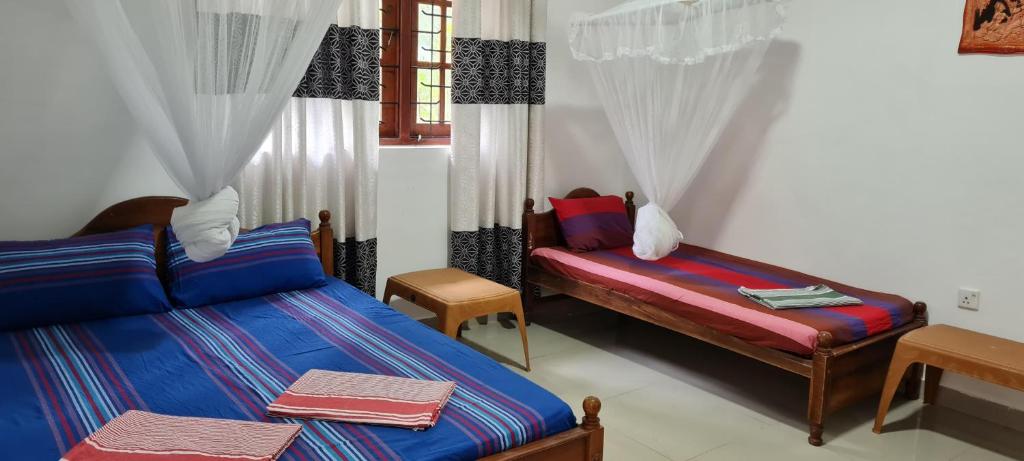 a bedroom with two beds and a window with curtains at Wimala B&B in Bentota
