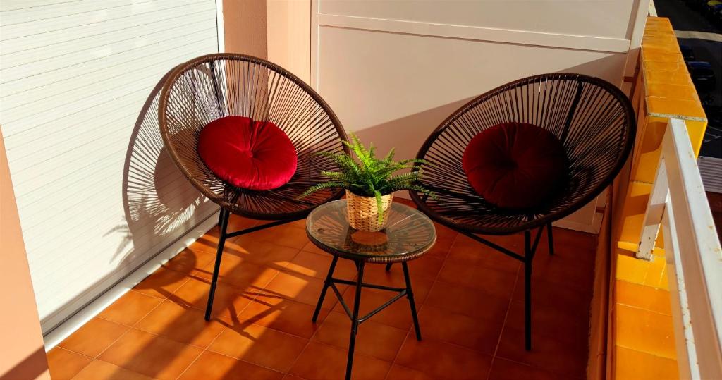 トッサ・デ・マールにあるApartament Marinaの赤いクッション付きの椅子2脚、植物付きのテーブル