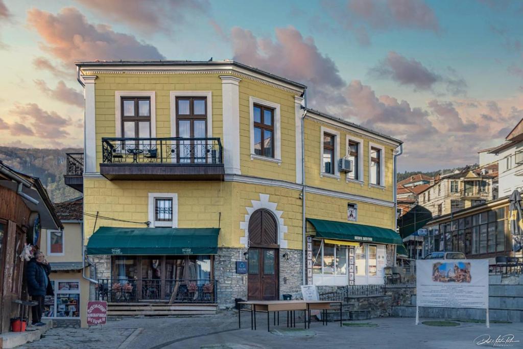 un edificio amarillo con un banco delante de él en Boutique Hotel St Nikolas by Skar en Kruševo