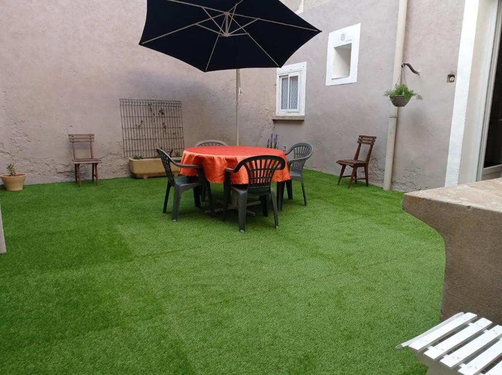 un patio avec une table, des chaises et un parasol dans l'établissement le gite de flavie, à Montpeyroux
