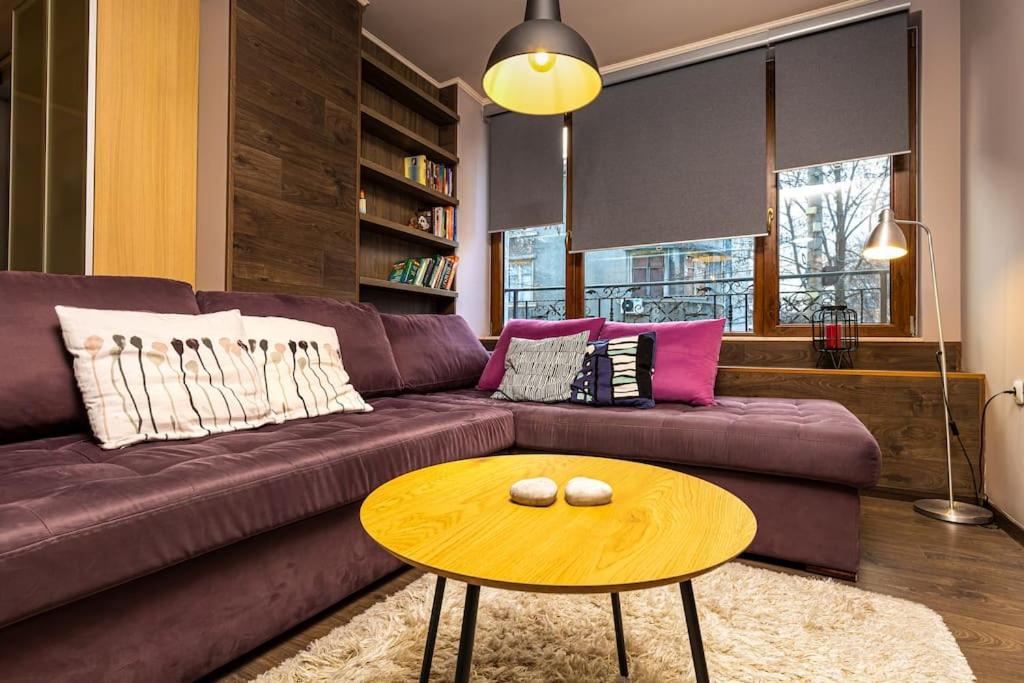 ein Wohnzimmer mit einem braunen Sofa und einem Tisch in der Unterkunft Dufti Home in Plovdiv Center & Old Town / Kapana in Plowdiw