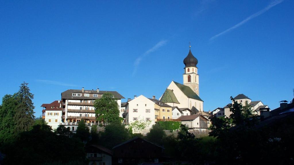 ein hohes Gebäude mit einem Turm und einer Kirche in der Unterkunft Hotel Rose Wenzer in Vols am Schlern