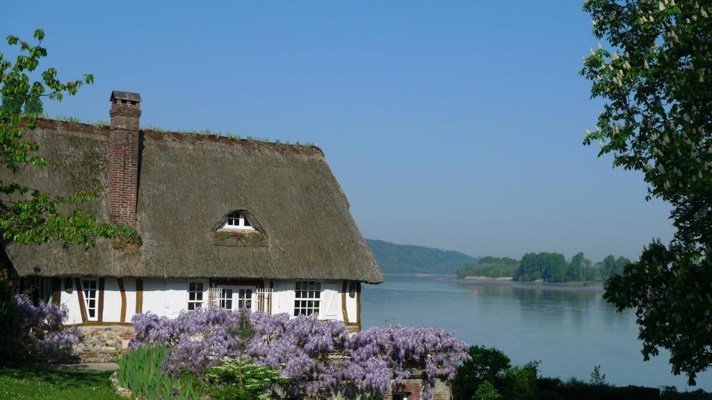 une maison au toit de chaume à côté d'une rivière dans l'établissement La Bonne Auberge - Seine Panorama SAS, à Vieux-Port