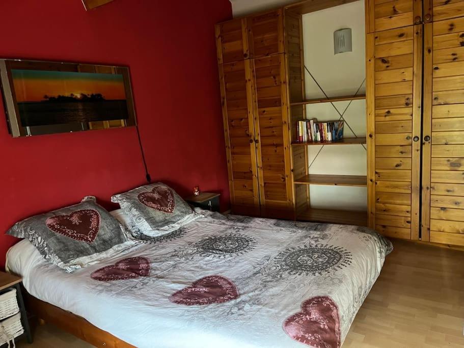 sypialnia z łóżkiem i czerwoną ścianą w obiekcie Maison de vacances Biscarrosse Lac w mieście Biscarrosse