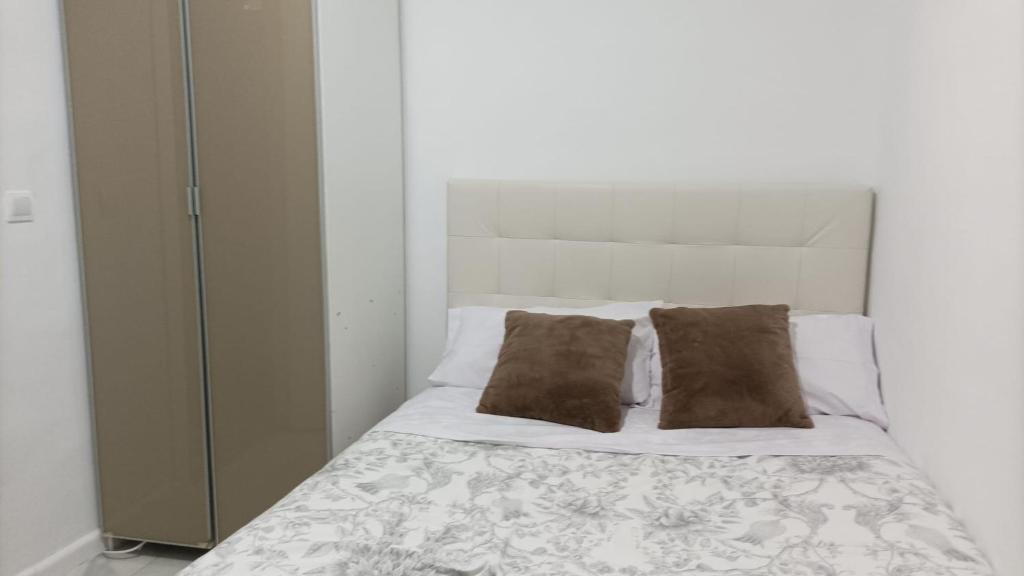 1 cama blanca con 2 almohadas y armario en Habitación cerca centro de Madrid, en Madrid