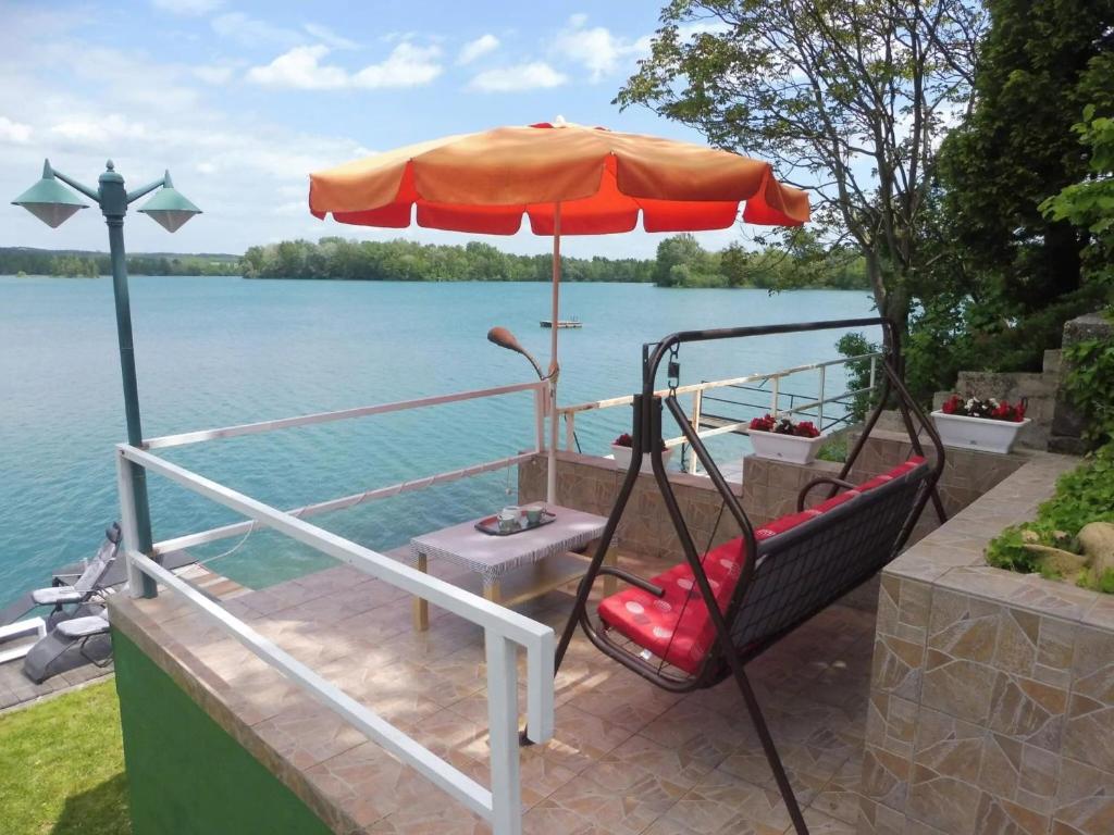 a swing on a boat with an umbrella at DÉZSAFÜRDŐS TÓPARTI NYARALÓ in Gyékényes