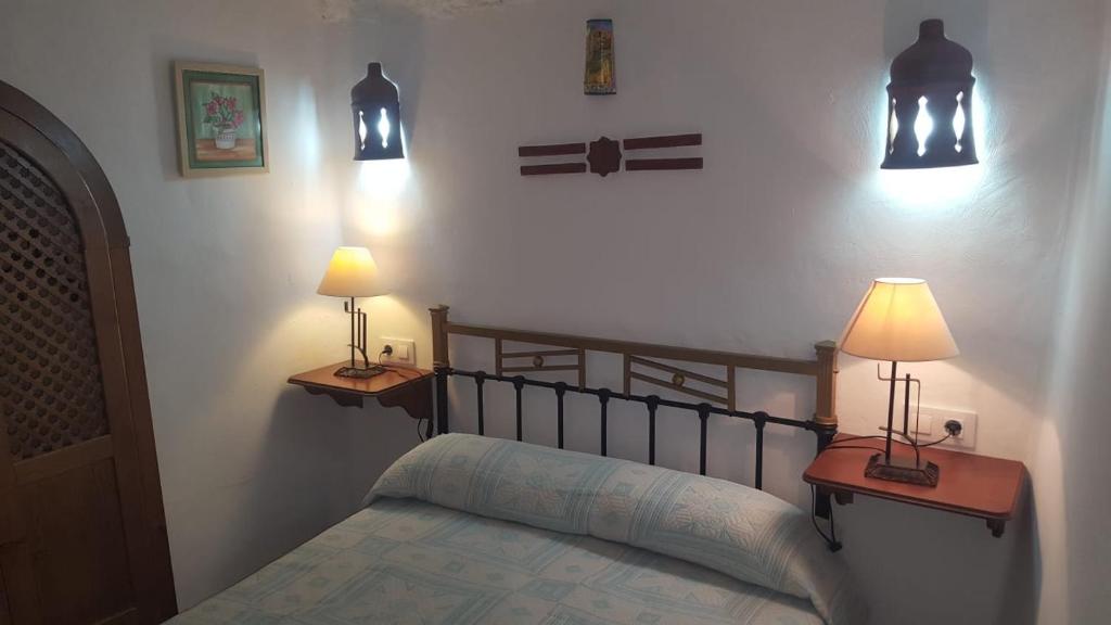 1 dormitorio con 1 cama y 2 luces en la pared en CASAS CUEVAS ELVIRA, en Hinojares