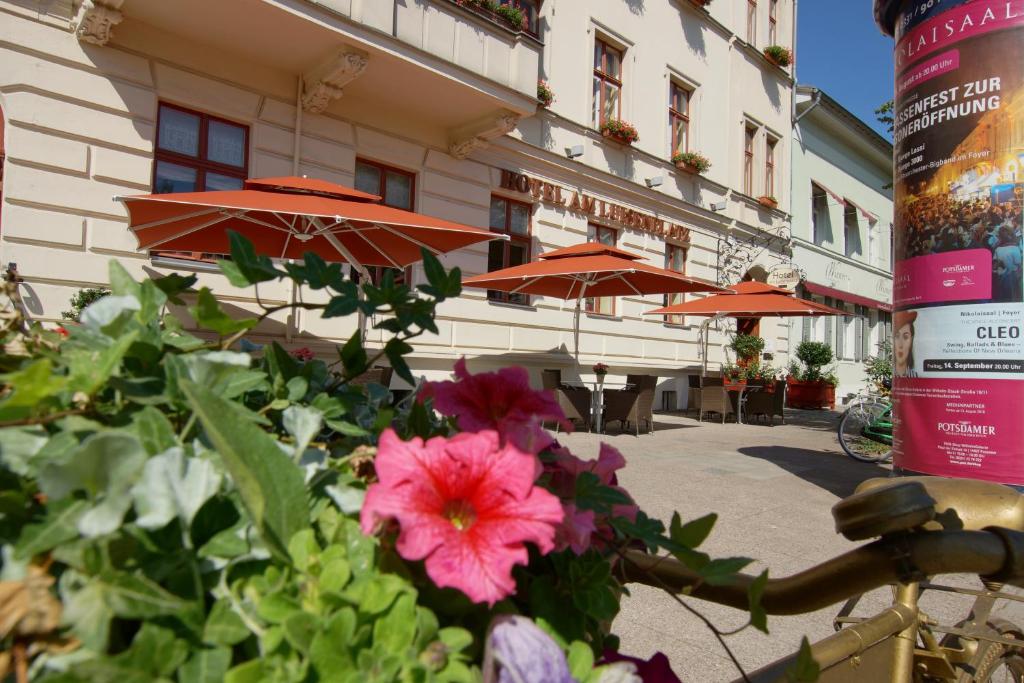 a bunch of flowers in front of a building with umbrellas at Hotel am Luisenplatz in Potsdam