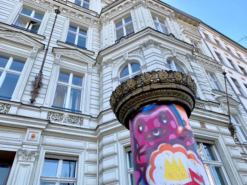 ein hohes Gebäude mit einem bunten Gemälde auf einer Stange in der Unterkunft Grand Hostel Berlin Classic in Berlin