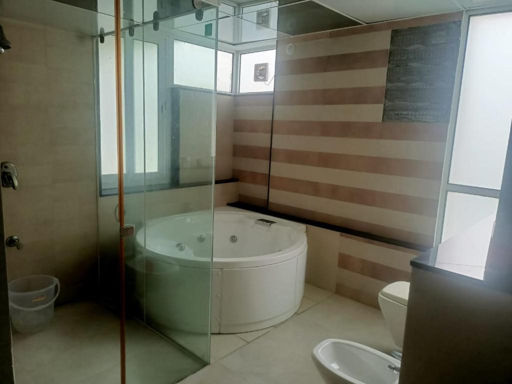 a bathroom with a shower and a tub and a toilet at Royal Nest - Luxury Stay in Pune