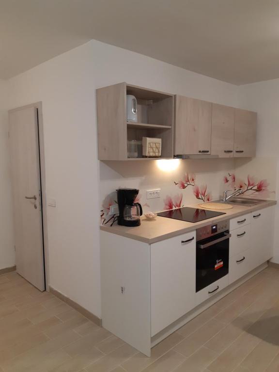 a kitchen with white cabinets and a stove top oven at ALPSKA ROŽA in Kranjska Gora