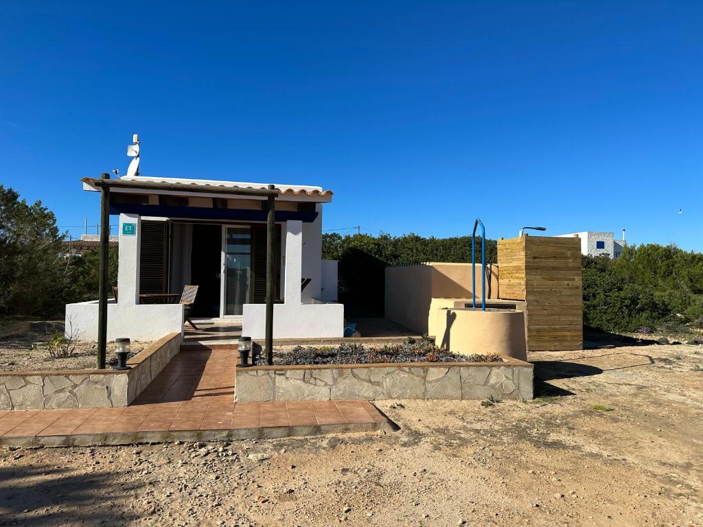 een klein huis met een veranda met een dak bij Estudi Es Carnatge in Playa Migjorn