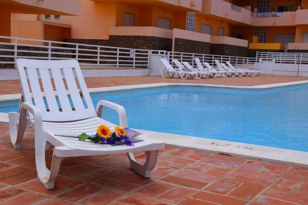a white chair sitting next to a swimming pool at Apartamento Duja in Cabanas de Tavira