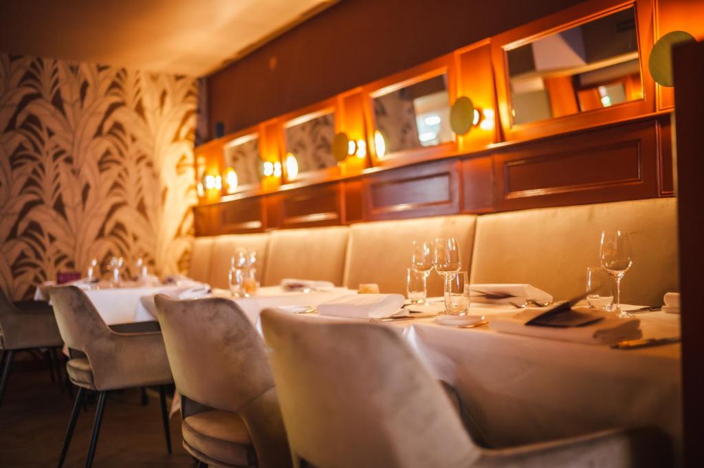 een restaurant met witte tafels, stoelen en verlichting bij Hotel Halbert in Groningen