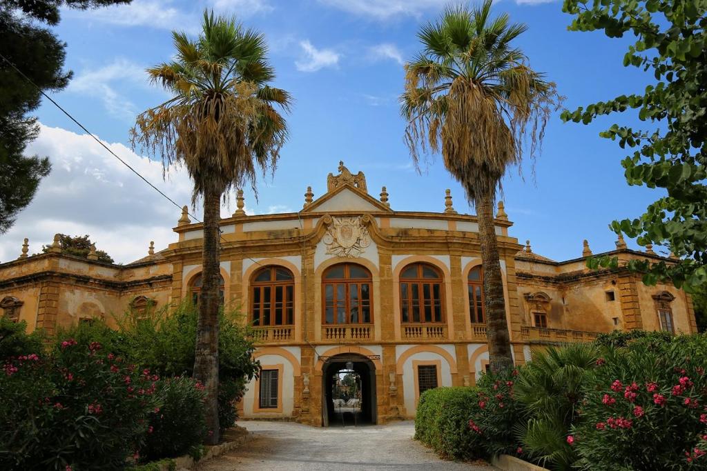 een oud gebouw met palmbomen ervoor bij Casa Vacanze L'Ortensia in Bagheria
