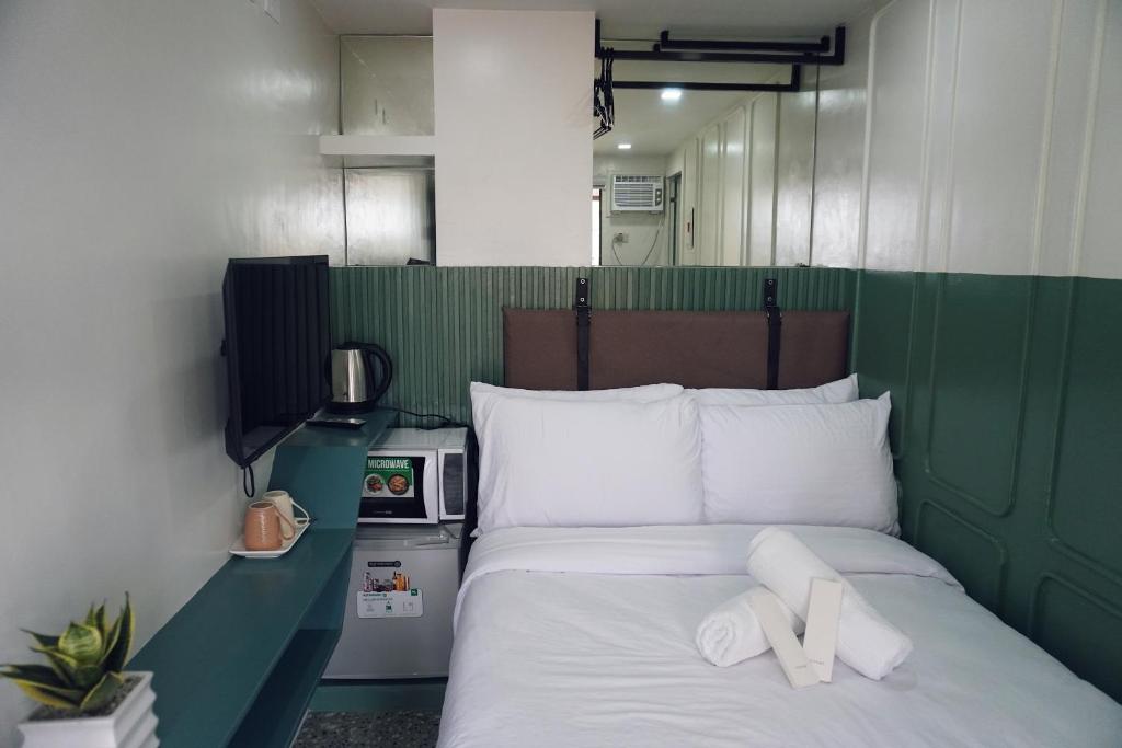 Una cama verde y blanca con dos toallas blancas. en Cebu Backpackers Hostel en Cebu City