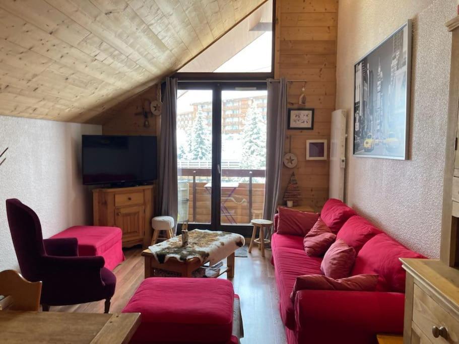 sala de estar con sofá rojo y TV en Appartement Alpe Huez 8 personnes centre station en LʼHuez