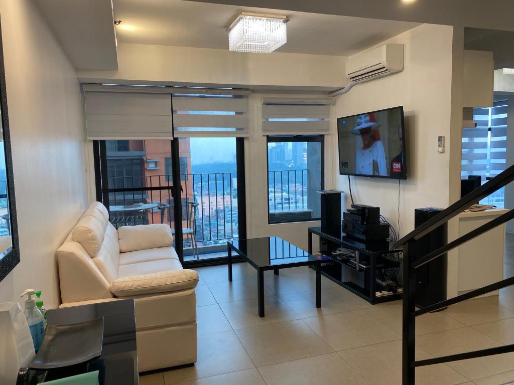 een woonkamer met een witte bank en een tv bij Penthouse suite at Porto Vita Towers in Cubao Quezon City in Manilla