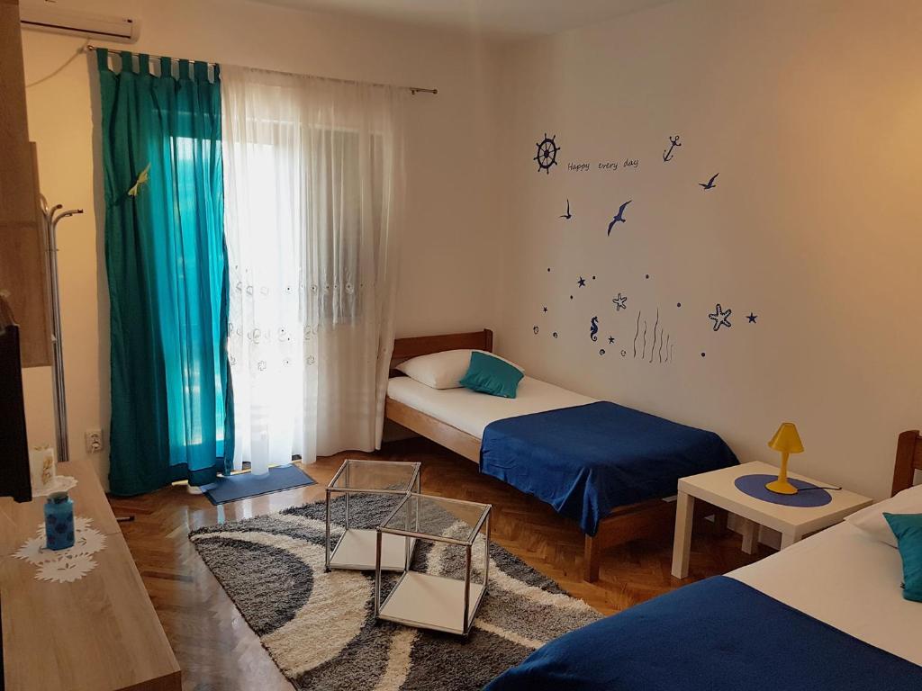 sypialnia z 2 łóżkami i oknem z ptakami na ścianie w obiekcie Apartments Luna w mieście Pag