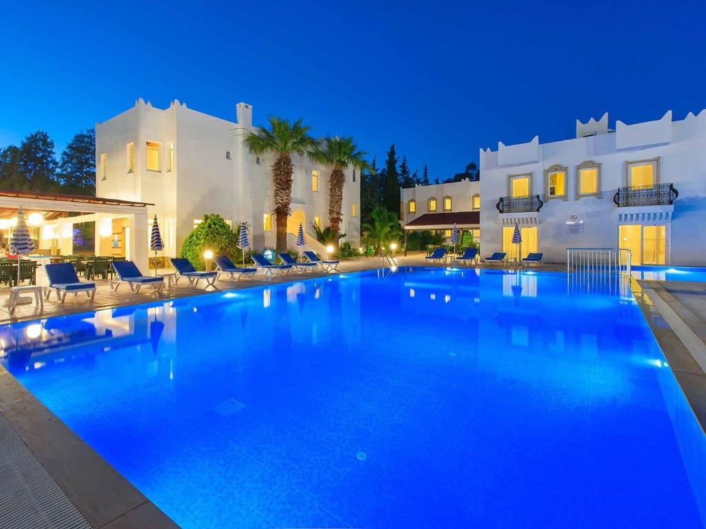 a large swimming pool with blue water at night at Bitez Kassandra Hotel in Bitez