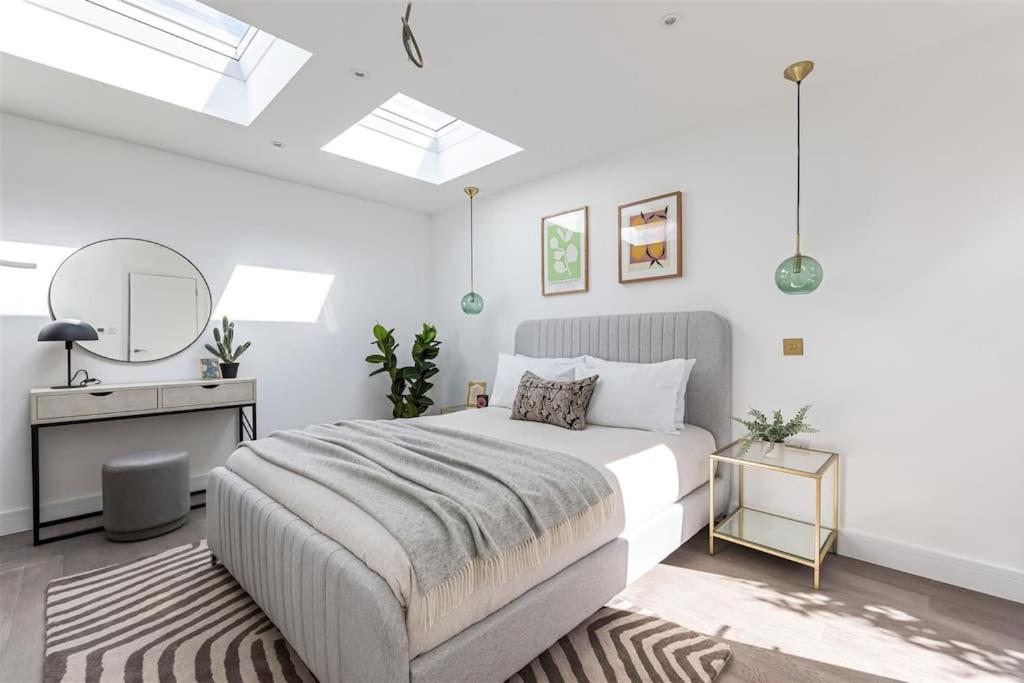 a white bedroom with a bed and a desk at Cozy Leyton House with Garden and Small Terrace in London