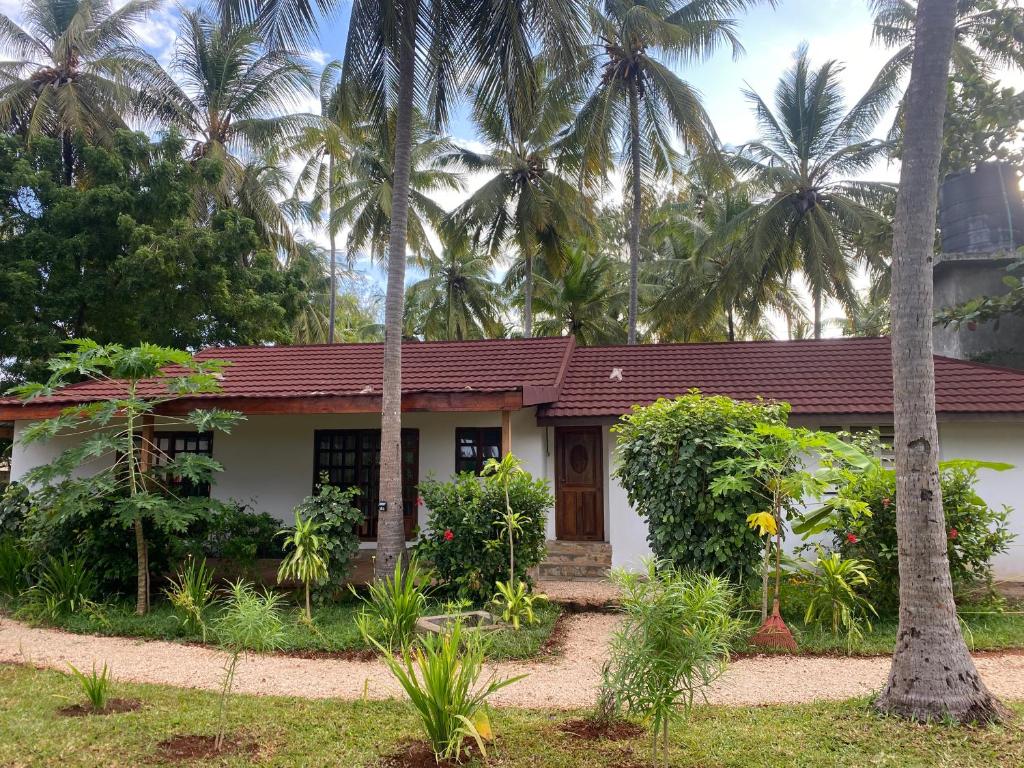 a house with palm trees in front of it at Garden Beach Apartment Zanzibar in Pwani Mchangani