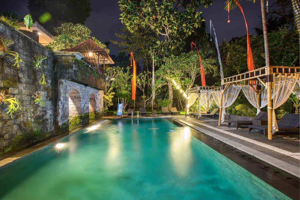 a swimming pool in a backyard at night at Alas Petulu Villa Resort and Spa in Ubud