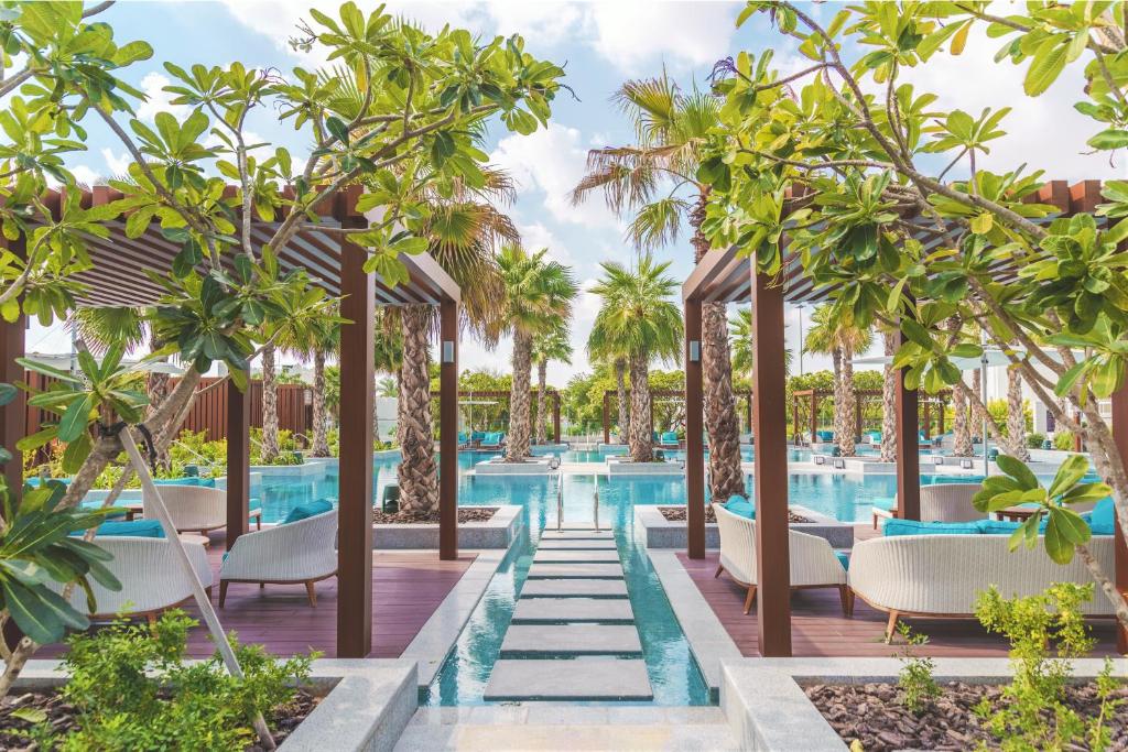 una foto di una piscina in un resort con sedie e alberi di Al Messila, A Luxury Collection Resort & Spa, Doha a Doha