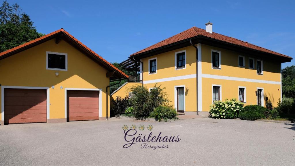 Ried im Traunkreis的住宿－Gästehaus Reingruber，车道上设有车库的大型黄色房屋
