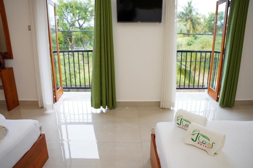 a room with two beds and a tv and a balcony at J Leaf Hotel By Blue Bird in Negombo