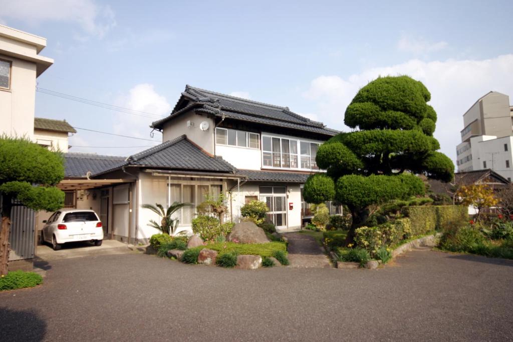 a house with a tree in front of it at Happy Neko in Beppu