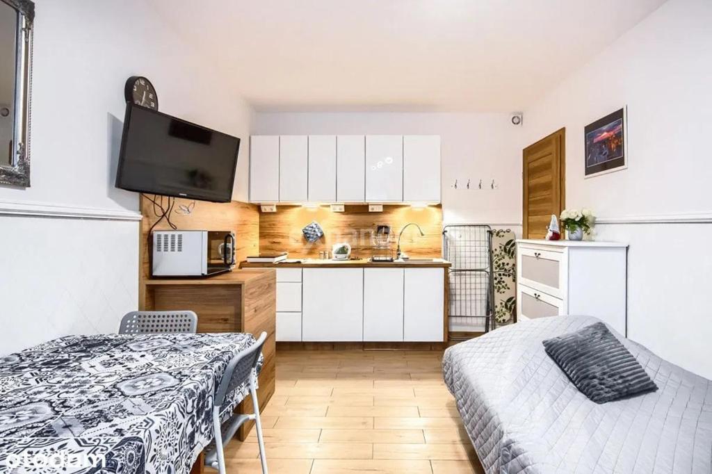 - une cuisine avec des placards blancs et un lit dans une chambre dans l'établissement LUKSUSOWY Gaj Apartament, à Wrocław