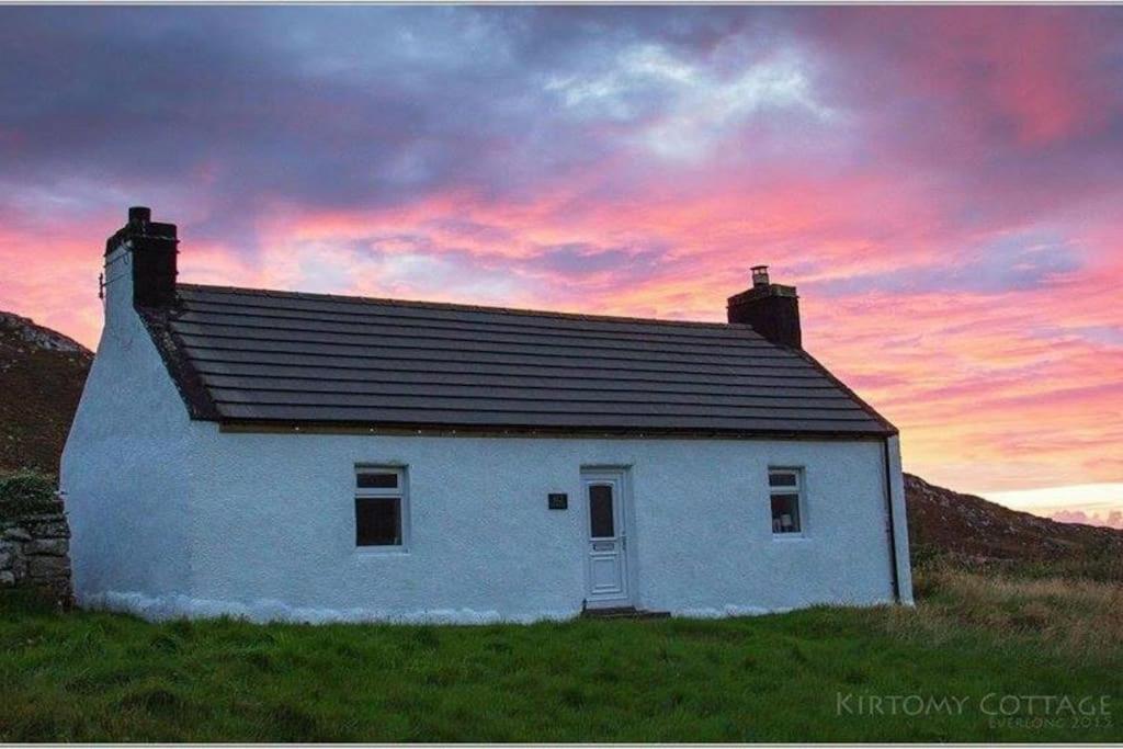 a white house in a field with a sunset at Kirtomy Cottage, Kirtomy, near Farr Beach, Bettyhill and Thurso in Farr