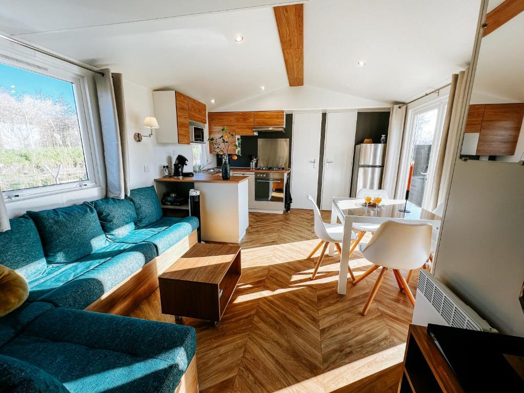 ein Wohnzimmer mit einem blauen Sofa und einem Tisch in der Unterkunft De Strandhoed Renesse, new & luxe chalet with garden en close to centrum & beach! in Renesse