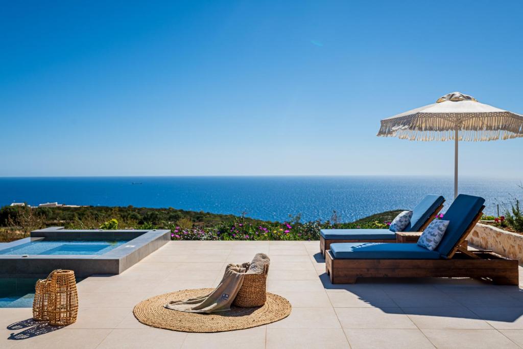 a patio with chairs and an umbrella and a pool at Terra Lucis Mountain Residences in Agios Leon